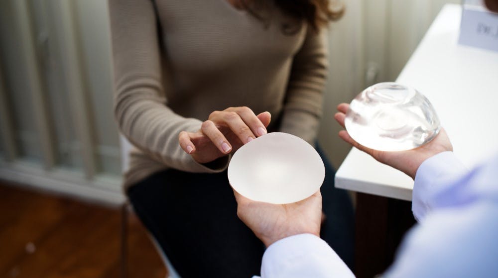 surgeon shows textured and smooth breast implants